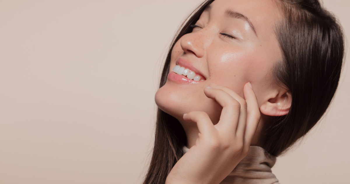 Woman with firm skin touching her face while smiling.